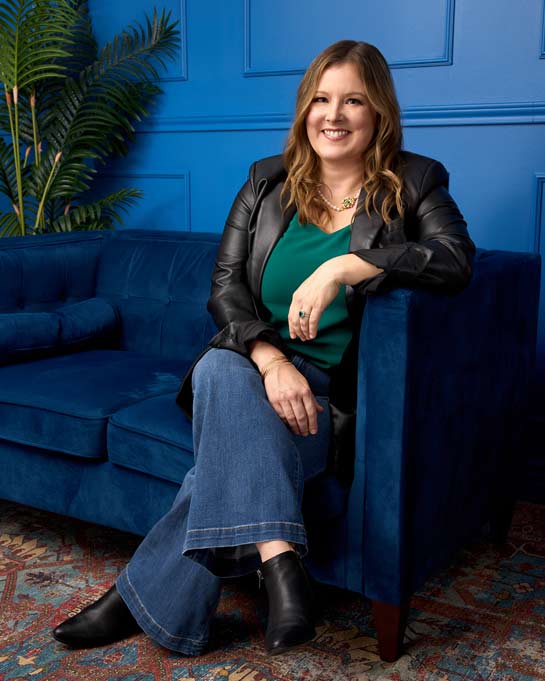 Woman posing on a blue couch for a personal branding session.