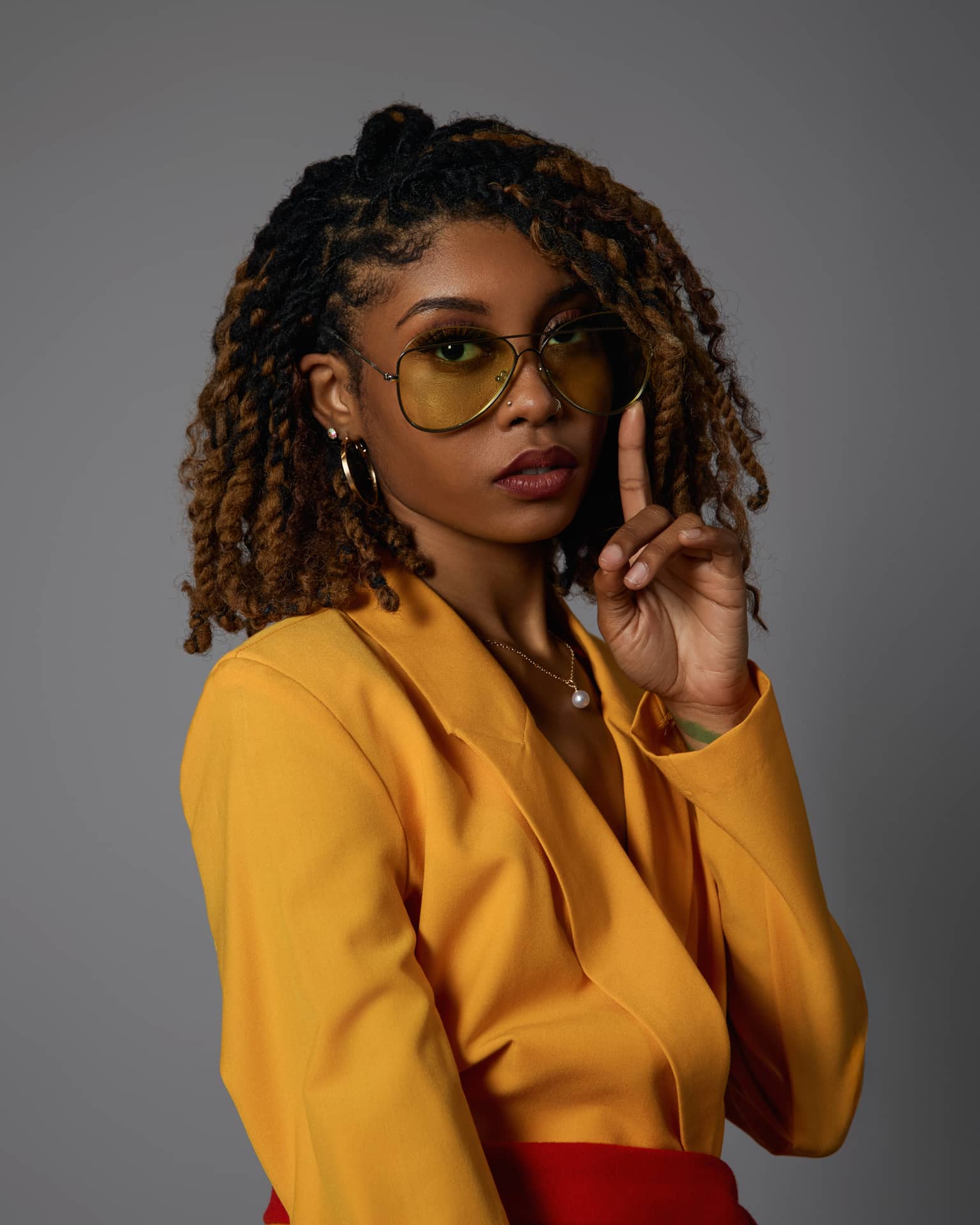 A stylish woman wearing a yellow double-breasted jacket and red accessories, including over-the-knee boots